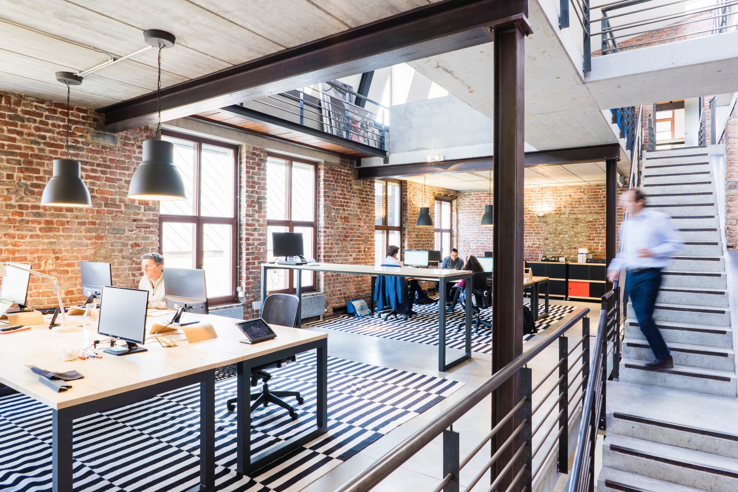 An open-plan office across two levels, teams working at their desks