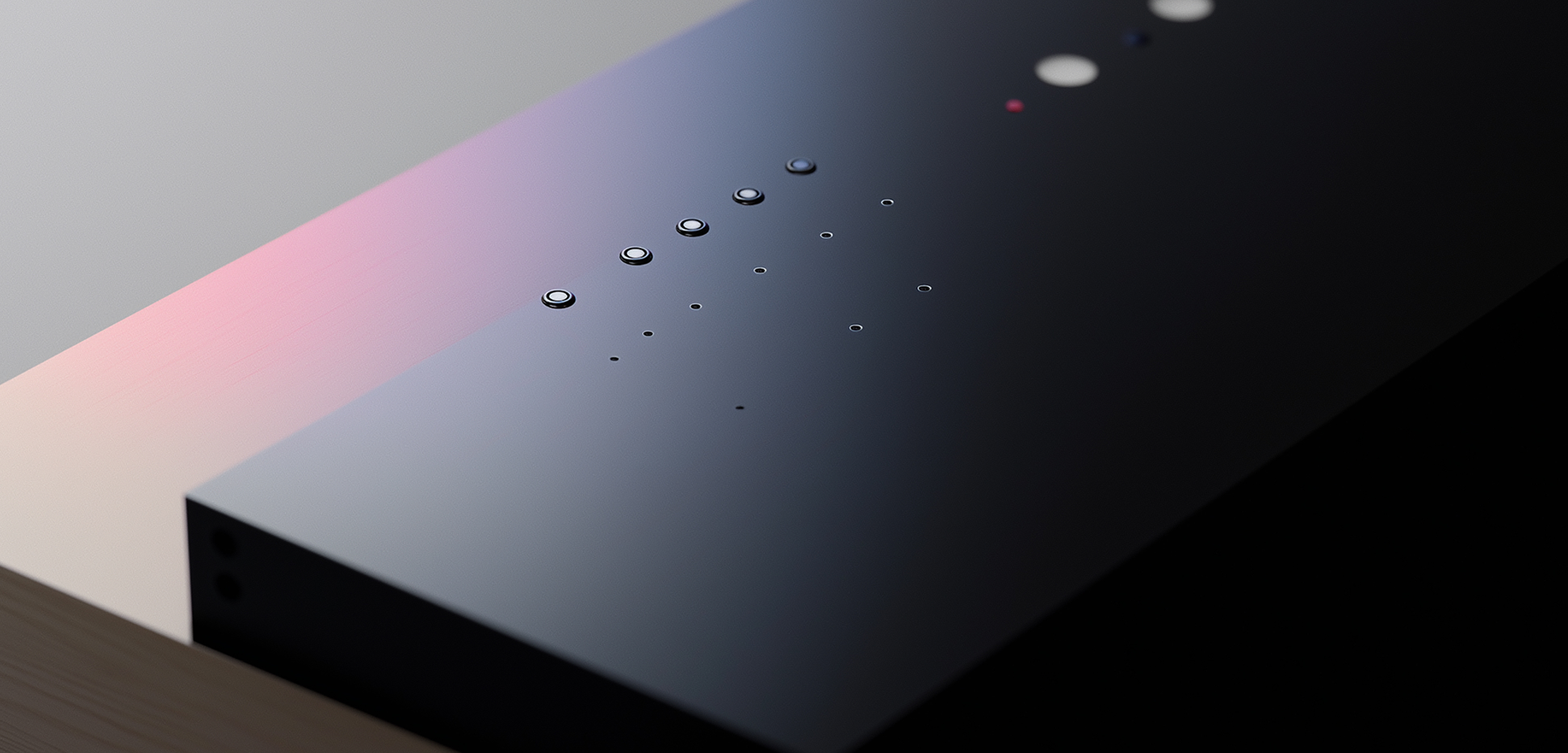 Abstract close-up of a dark minimal surface with small speaker grille dots.